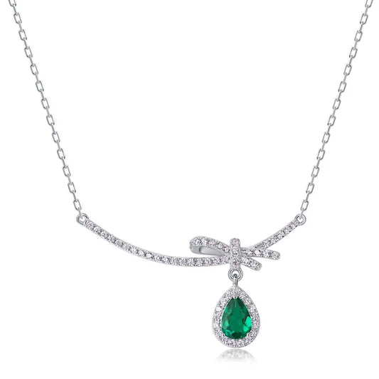 Bow and heart pendant with an emerald-cut lab emerald and round brilliant accent stones in silver-plated sterling silver
