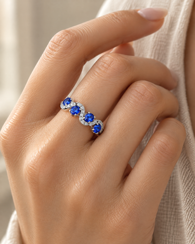 Hand wearing the Sapphire-Blue Wave Band Ring, blue cubic zirconia in rhodium-plated sterling silver